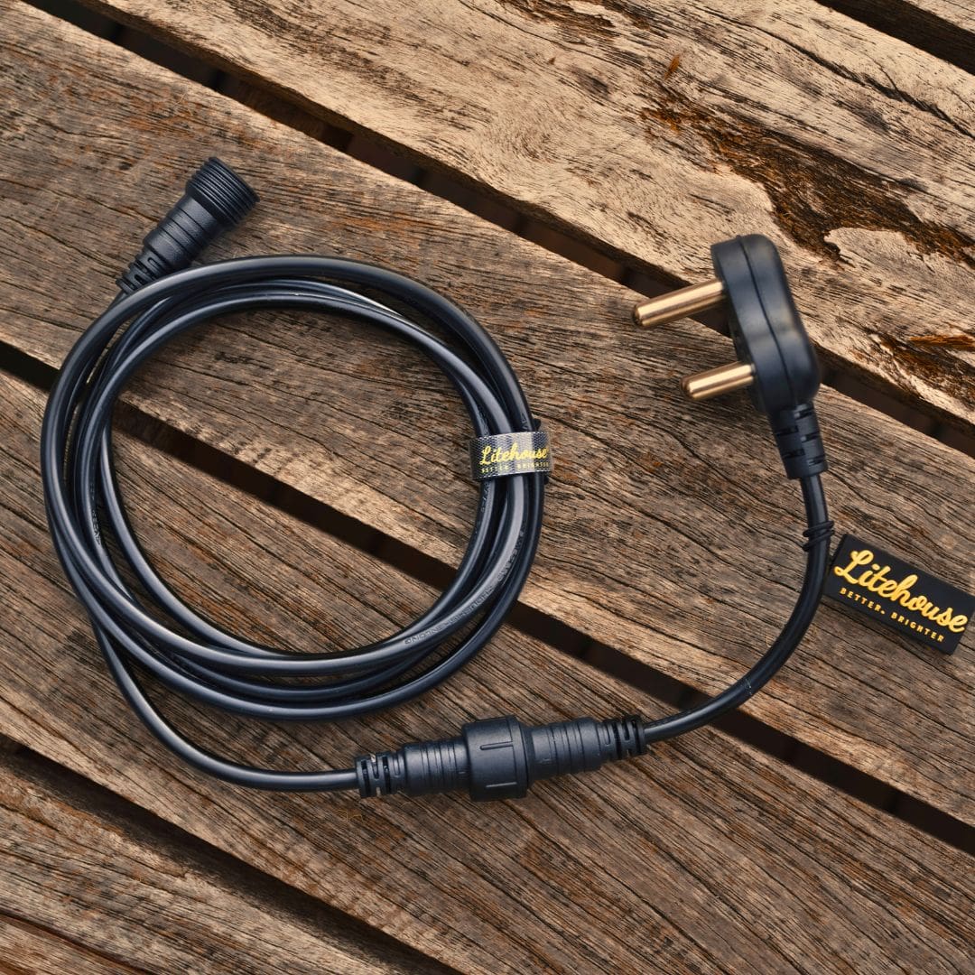 Coiled black electrical cable with a plug on a wooden surface, featuring the Litehouse brand.