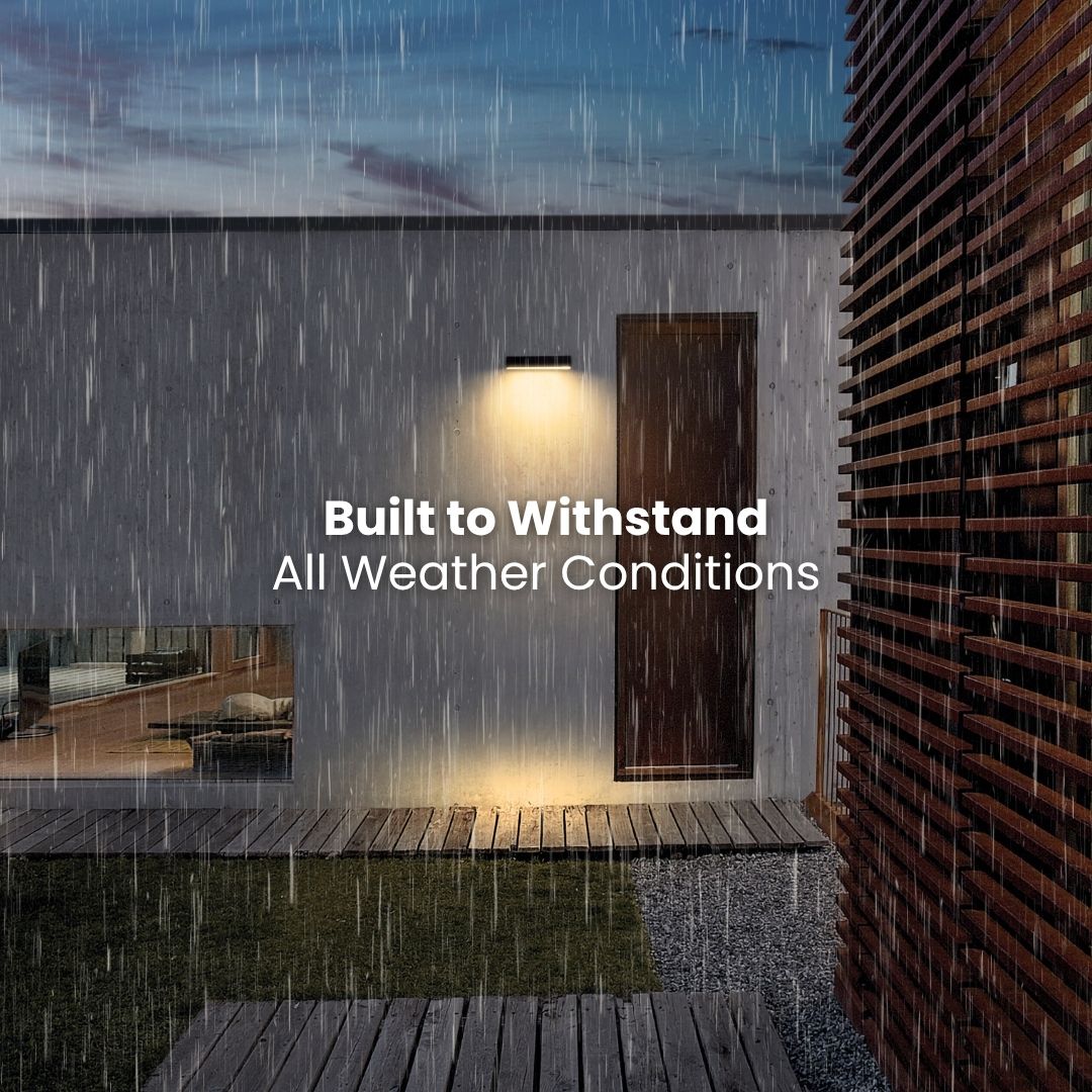 Ambiente esterno con pioggia e applique, terrazza in legno ed esterno di un edificio moderno con la scritta “Costruito per resistere a tutte le condizioni atmosferiche”.