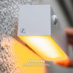 Applique da esterno con luce gialla brillante, logo del marchio visibile e scritta "Enhanced Safety & Security".